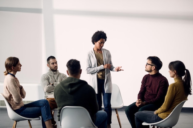 African American woman standing while talking during group therapy meeting