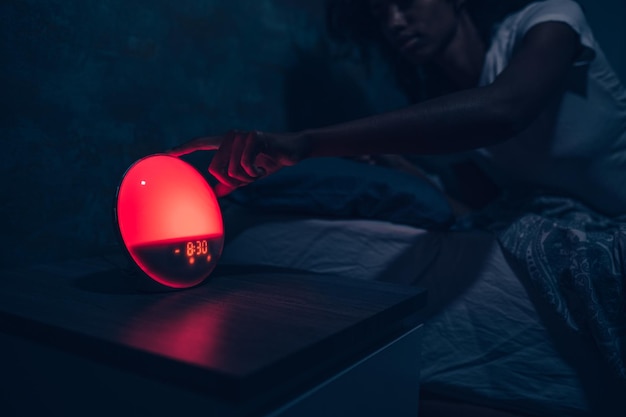 African American woman turning off alarm clock