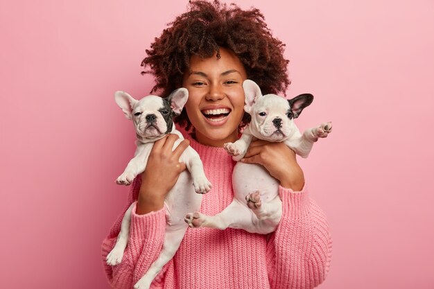 子犬を保持しているピンクのセーターを着ているアフリカ系アメリカ人の女性