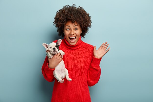 Афро-американская женщина в красном свитере держит собаку