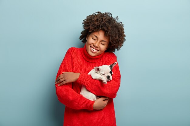 African American woman wearing red sweater holding dog