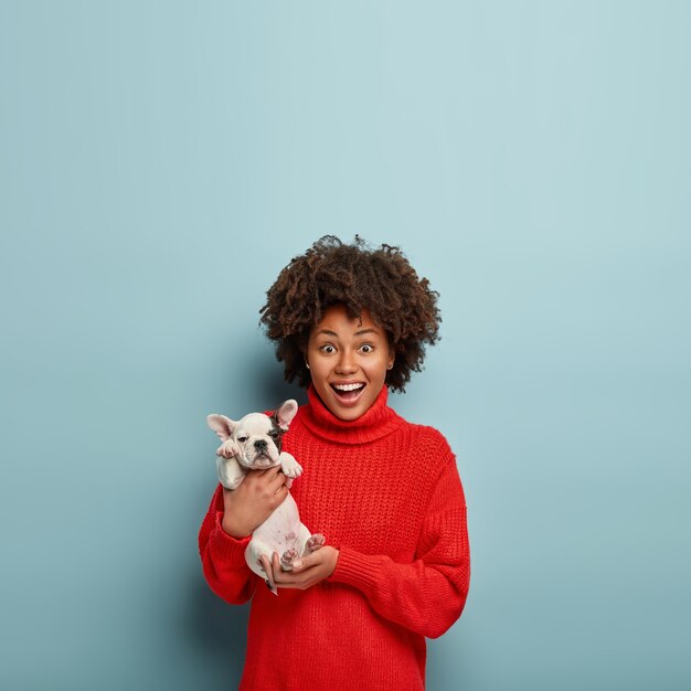 African American woman wearing red sweater holding dog