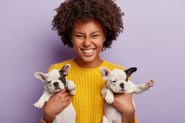 Donna afro-americana che indossa un maglione giallo che tiene i cuccioli