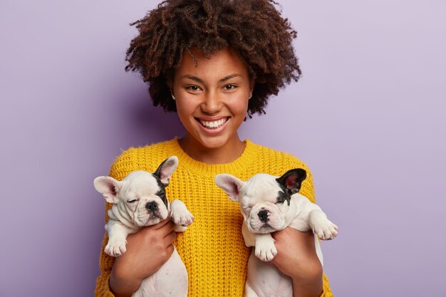 Donna afro-americana che indossa un maglione giallo che tiene i cuccioli