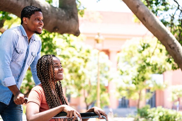 그녀의 남자 친구와 함께 공원에서 산책을 즐기는 휠체어에 아프리카 계 미국인 여자