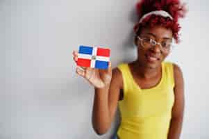 Free photo african american woman with afro hair wear yellow singlet and eyeglasses hold dominican republic flag isolated on white background