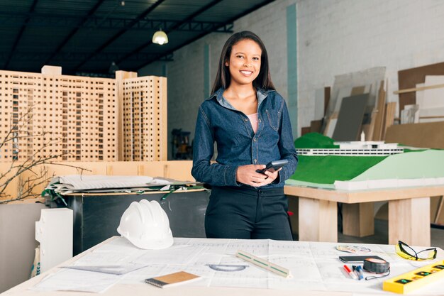 African American woman with calculator near table with safety helmet and equipments