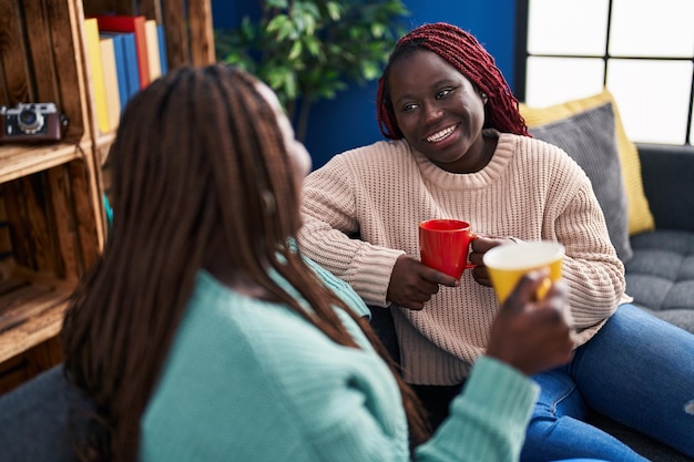 집에서 소파에 앉아 커피를 마시는 아프리카계 미국인 여자 친구