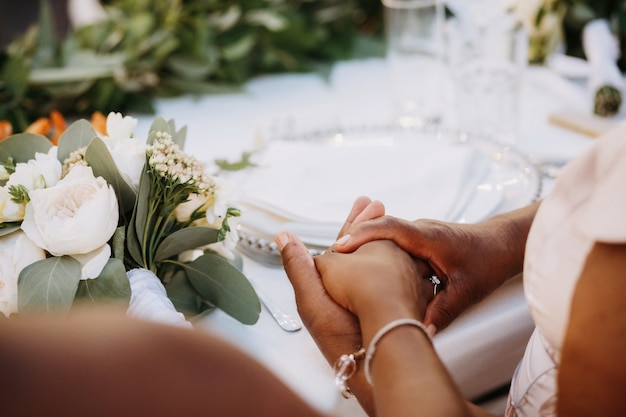 African American women hold their hands together sitting at the dinner table