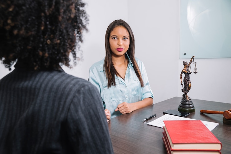 Free Photo african american women sitting at table near document, pen, figure and gavel