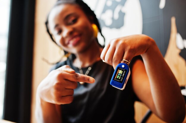 African american women with pulse oximeter on hand measuring oxygen saturation level