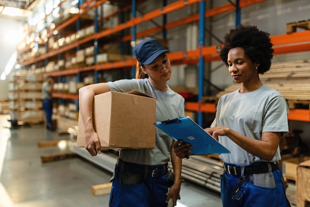 African American worker and her coworker reading order list before the shipment while working in a warehouse