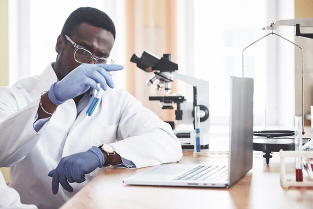 Афро-американский рабочий работает в лаборатории, проводит эксперименты.