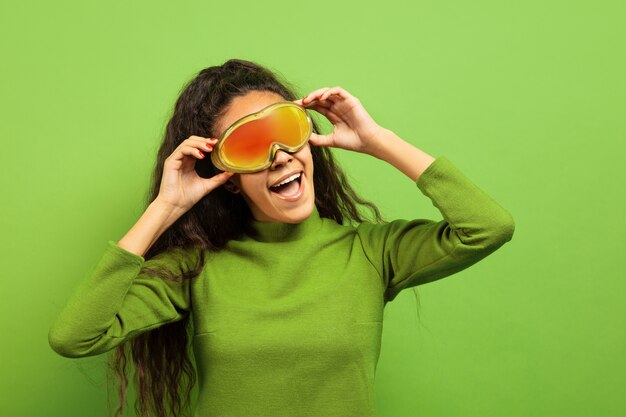 African-american young brunette woman's portrait in ski mask on green  space