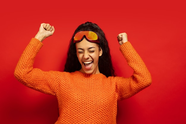 Free photo african-american young brunette woman's portrait in ski mask on red  space