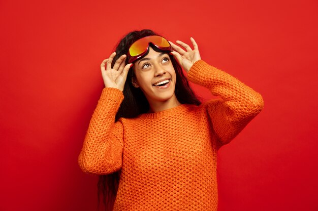 African-american young brunette woman's portrait in ski mask on red