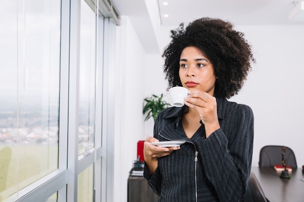 African American young lady with cup near window