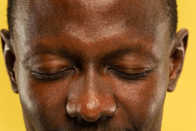 아프리카 계 미국인 젊은 남자의 노란색 스튜디오 배경에 초상화를 닫습니다. 피부가 잘 관리 된 아름다운 남성 모델. 인간의 감정, 표정, 판매, 광고의 개념. 눈과 뺨.