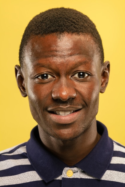 Free photo african-american young man's close up portrait on yellow studio background. beautiful male model with well-kept skin. concept of human emotions, facial expression, sales, ad. looks happy and calm.