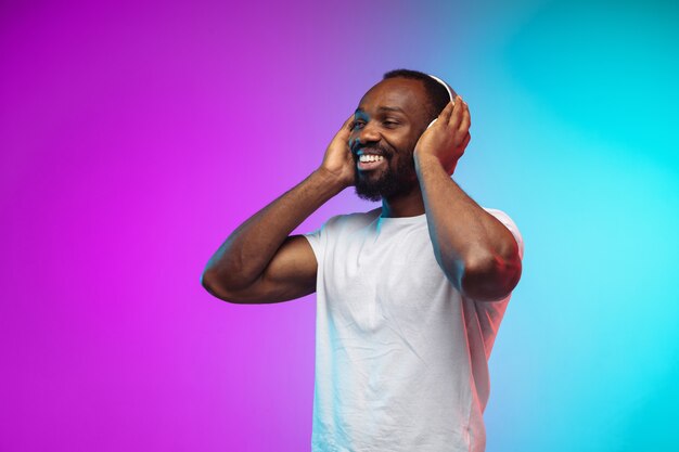 African-american young man's portrait on gradient studio in neon