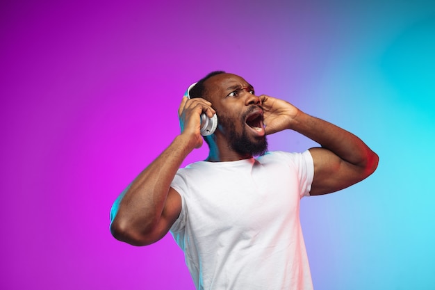 African-american young man's portrait on gradient studio in neon