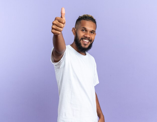 African american young man in white t-shirt looking at camera happy and cheerful smiling