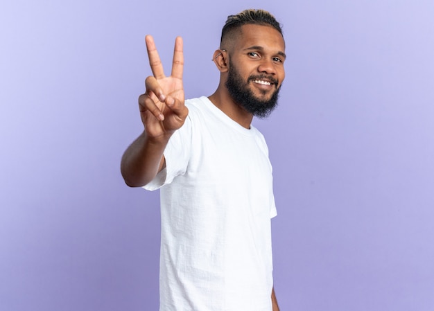 African american young man in white t-shirt looking at camera smiling confident showing number three