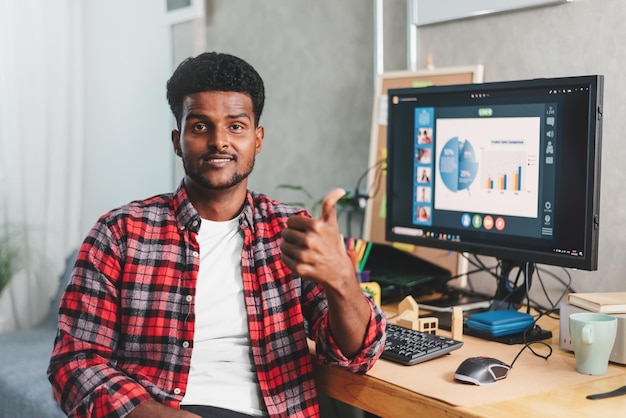 African american young man work at home showing thumb up for good work on the background of working desk