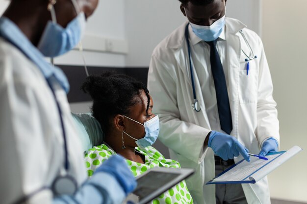 African american young patient with protective face mask against covid resting in bed