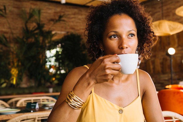 흰색 컵에서 커피를 마시는 아프리카 계 미국인 젊은 여자