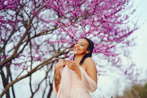 Foto gratuita giovane donna afroamericana, gli alberi con il bel colore rosa