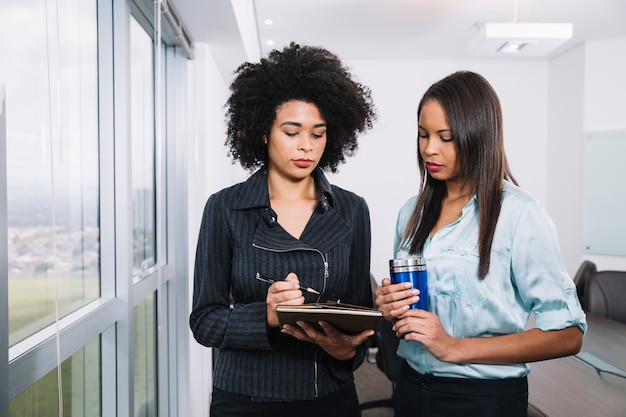 African American young women with vacuum cup and documents near window