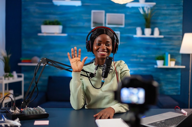 African blogger waving at audience while filming podcast. On-air production internet broadcast host streaming live content, recording digital social media
