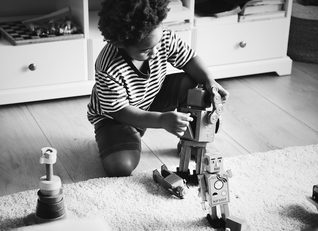 Free photo african boy playing with a robot at home