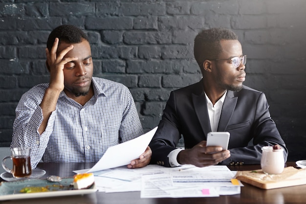 African businessman reading document in hands with frustrated look