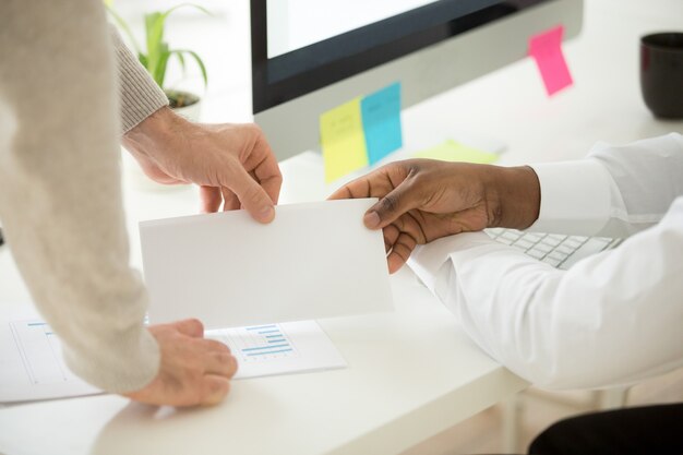 African businessman receiving envelope with bribe or money bonus, closeup