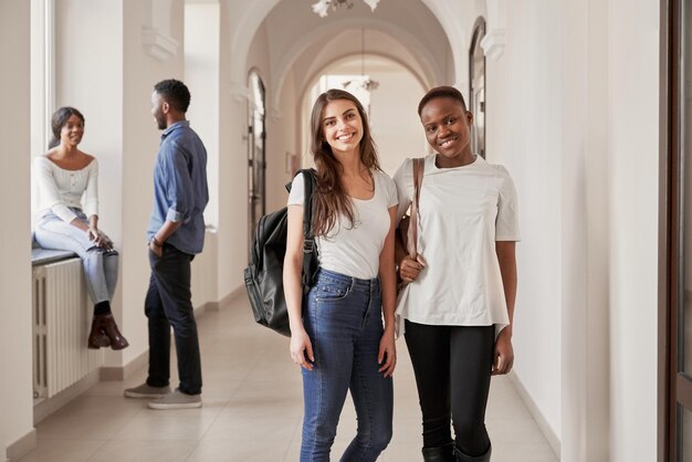 African and Caucasian female students resting on corridor