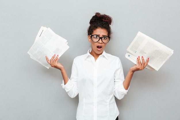 Free photo african confused business woman standing over grey wall