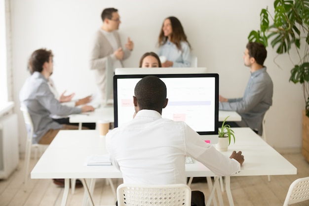 Free photo african employee working on computer in multiracial office, rear view