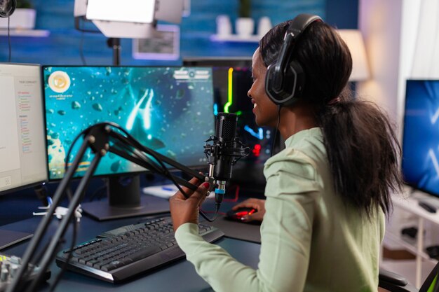 African esports player talking with team during live space shooter stream competiton. Streaming viral video games for fun using headphones and keyboard for online championship.