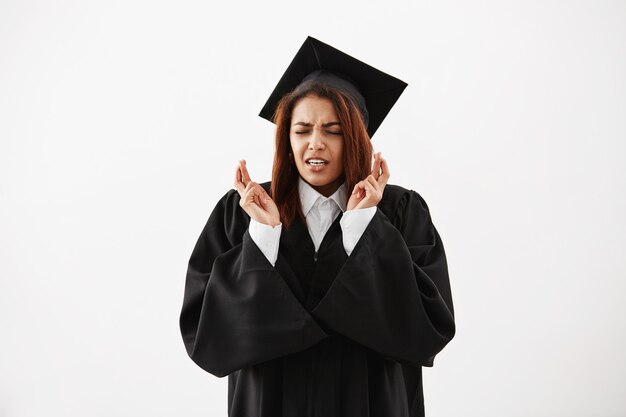 African female graduate in black mantle praying. Copy space.