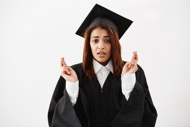 African female graduate in black mantle praying. Copy space.