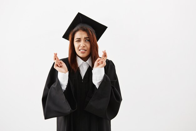 African female graduate in black mantle praying. Copy space.