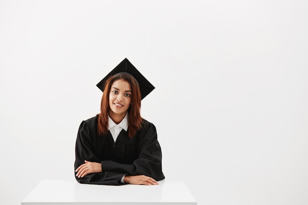 African female graduate smiling sitting. White background. Copy space.