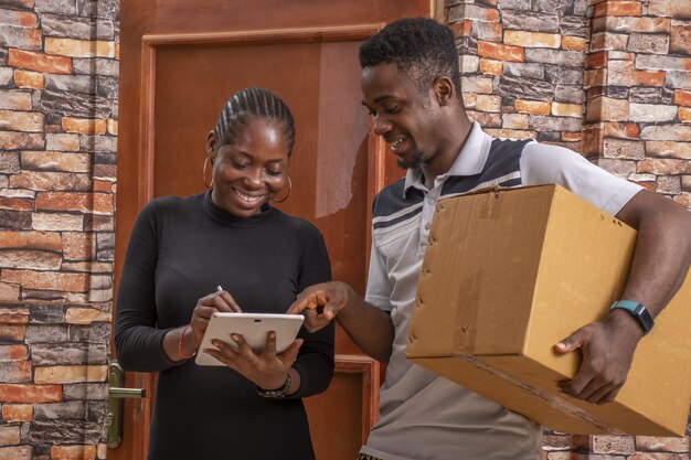 African female signing a proof of delivery while receiving a parcel from the courier