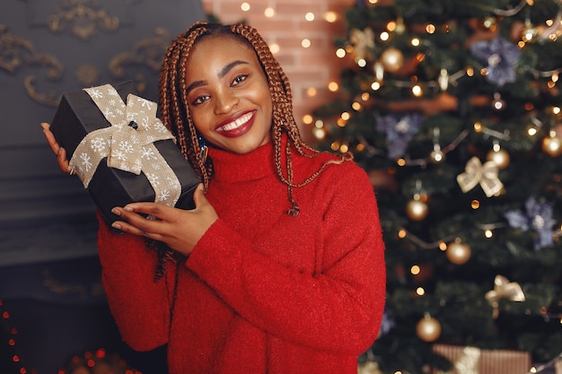 Ragazza africana in un addobbo natalizio / donna in un maglione rosso. anno nuovo concetto.