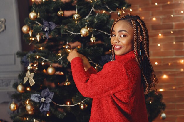Африканская девушка в рождественских украшениях / Женщина в красном свитере. Новогодняя концепция.