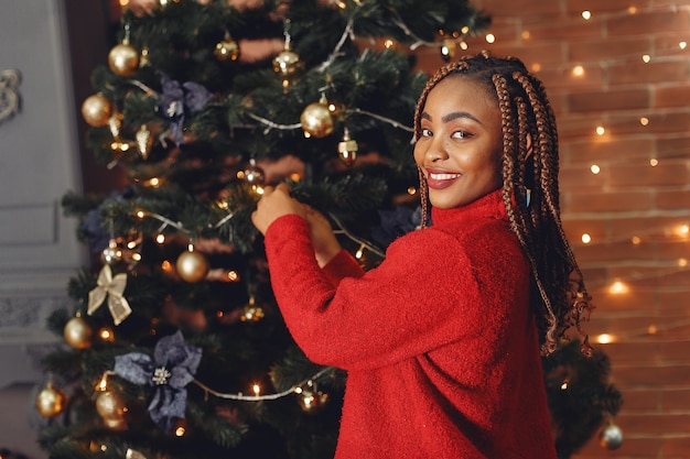 クリスマスの飾り付けのアフリカの女の子/赤いセーターの女性。新年のコンセプト。