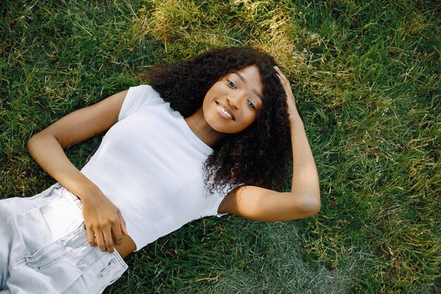 African girl looking at the camera while lying on a grass.