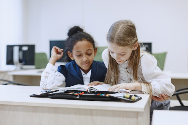 Free photo african girl sitting at the table. schoolgirls read a book during a break. children sit in a computer science class.